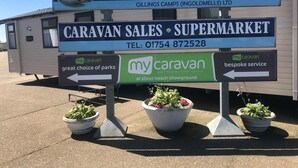 A sign for Silver Beach Caravan Park with a contact number and directions to a supermarket. - Beach Daze - Silver Beach - Standard (Skegness)