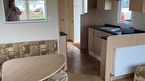 A compact kitchen with a dining area, a window, and a radiator. - Beach Daze - Silver Beach - Standard (Skegness)