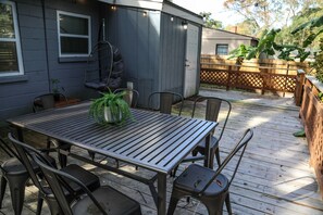 Une terrasse avec une table et des chaises en métal, un fauteuil suspendu et une clôture en bois.