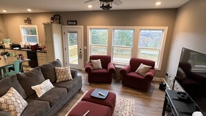 A living room with a gray couch, red armchairs, a TV, and a ceiling fan. - FAMILY LAKE ESCAPE AWAITS. Walk to Boat Ramp. Sleeps 12, with plenty of parking (Bronston)