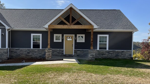 A two-story house with a stone foundation, a dark gray exterior, and a gabled roof. - FAMILY LAKE ESCAPE AWAITS. Walk to Boat Ramp. Sleeps 12, with plenty of parking (Bronston)