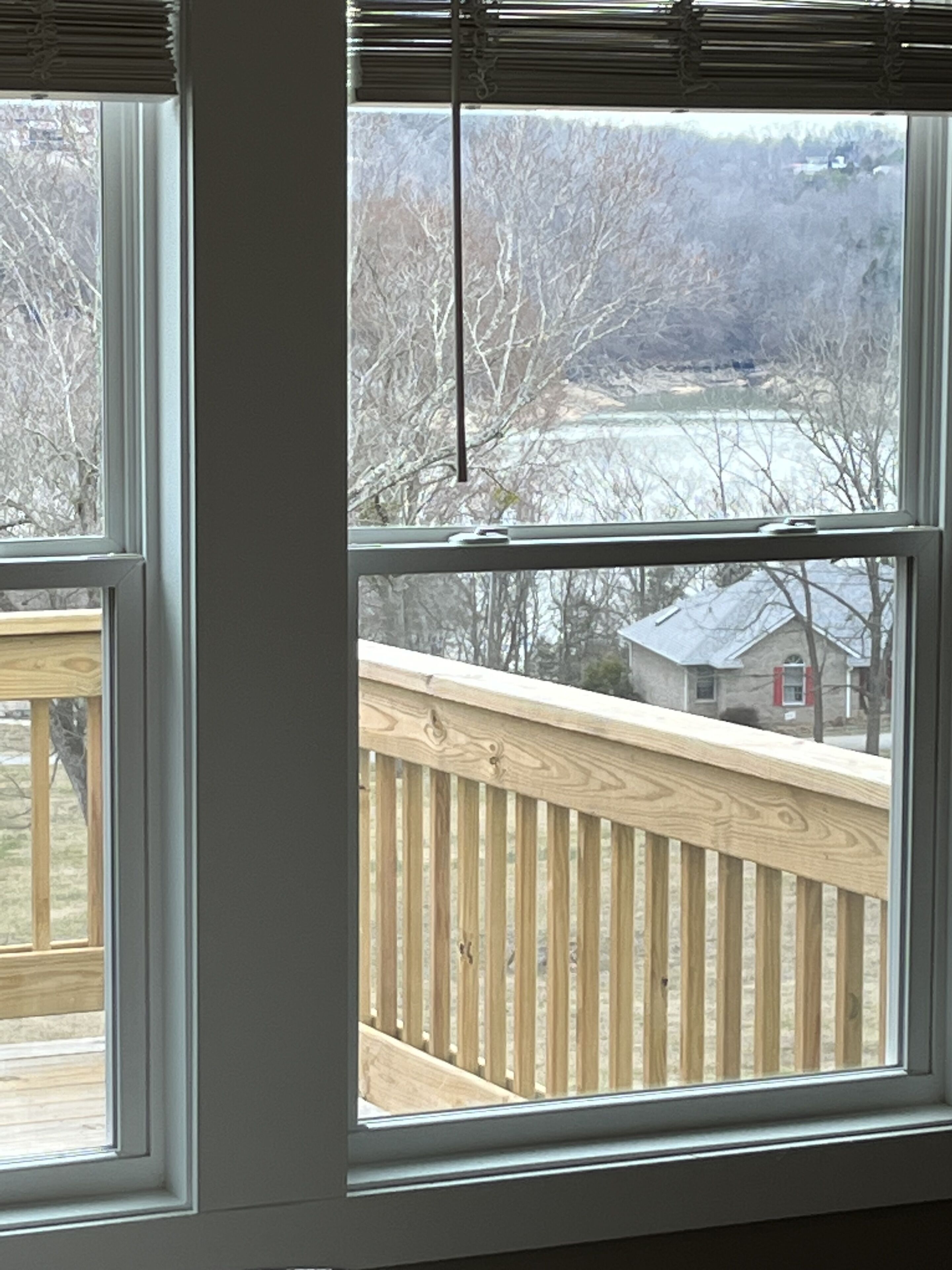 Une fenêtre donnant sur une terrasse en bois et une maison en arrière-plan.