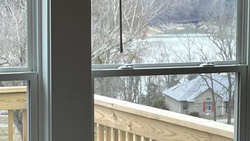 Une fenêtre donnant sur une terrasse en bois et une maison en arrière-plan.