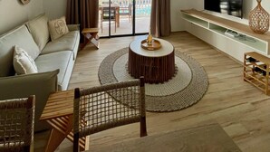 A modern living room with a sofa, a coffee table, a TV, and a balcony with a view of the sea. - Bella Vista 2 bedroom - Orient Bay (Collectivité de Saint-Martin)