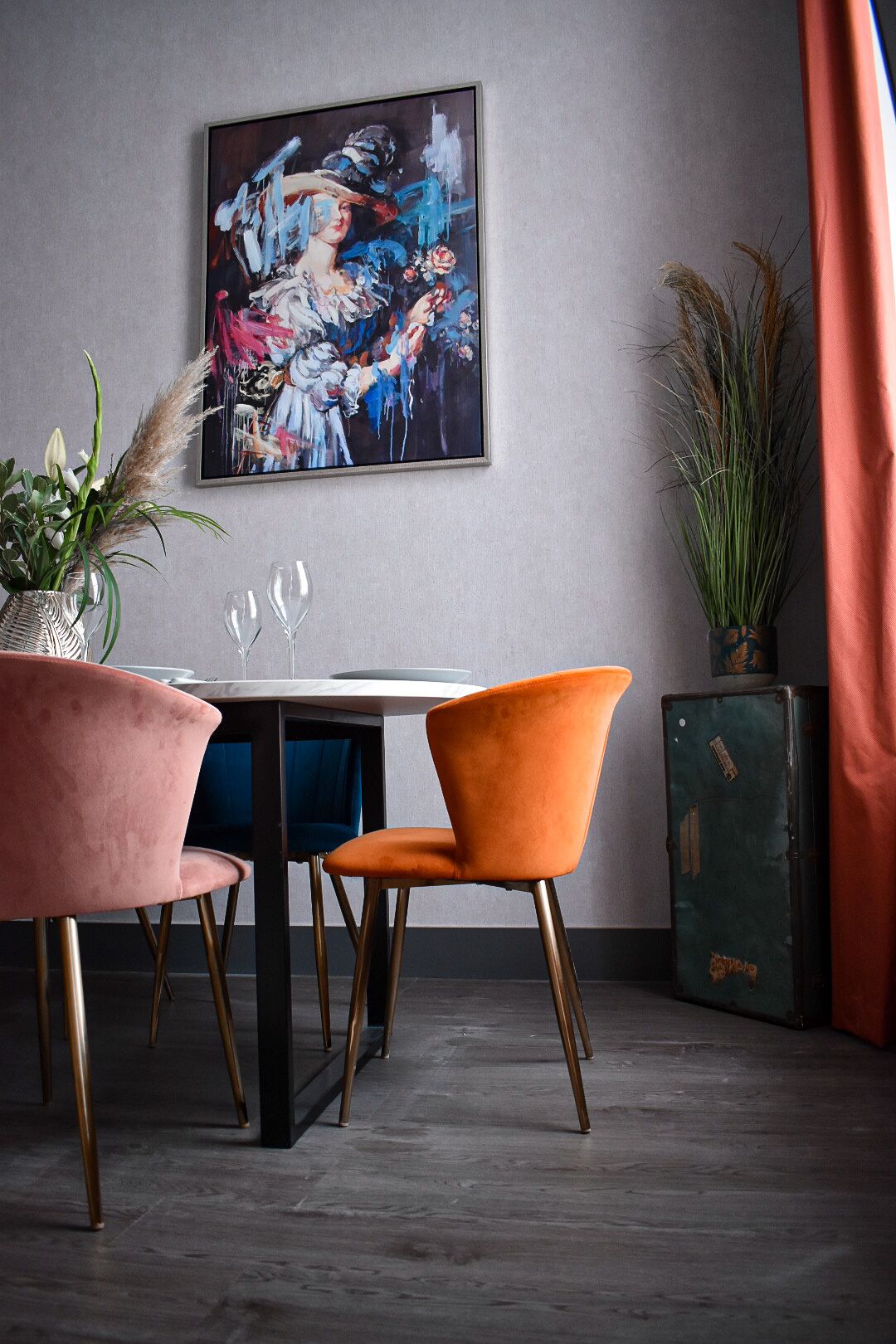 A dining area with a table, chairs, and a painting on the wall.