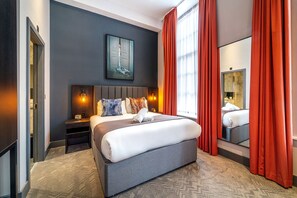 A modern hotel room with a large bed, a nightstand, a wall-mounted painting, and a large mirror. - Duke Street Townhouse by EPIC (Liverpool)