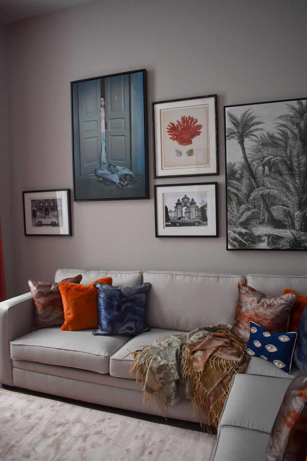 A living room with a grey sofa, colorful cushions, and framed artwork on the wall.