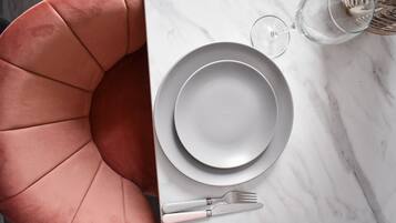 Una mesa de comedor con cubierta de mármol blanco, cubiertos y un vaso de agua.