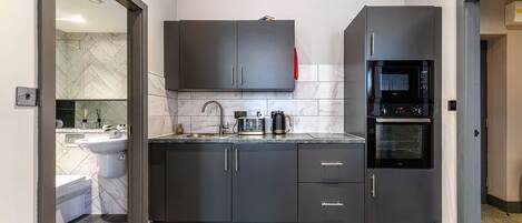 A modern kitchen with dark cabinets, a microwave, and a coffee maker on the countertop.