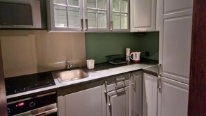 A compact kitchen with white cabinets, a stainless steel stove, and a microwave. - Beautiful place in the city center (Kraków)
