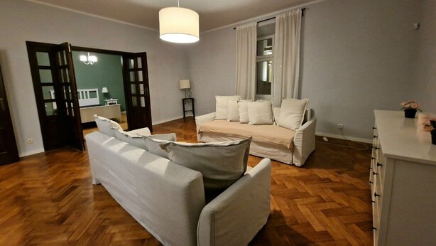 A modern living room with a sofa set, a dining area, and a kitchen counter. - Beautiful place in the city center (Kraków)