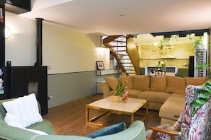 A modern living room with a sofa, a coffee table, and a staircase leading to a kitchen area.