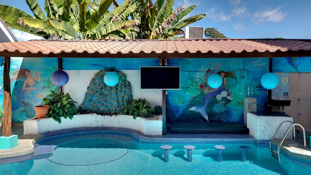 En swimmingpool med flisekant, en bænk og et muralmaleri med sødyr.