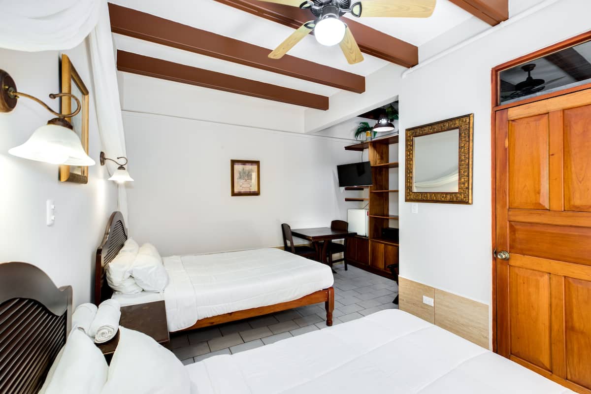 A hotel room with a bed, a desk, a chair, a TV, and a wardrobe.
