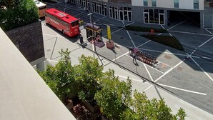 A modern hotel building with a prominent red vertical stripe, large windows, and a parking area with a red bus. - Hotspot Venice Ca Marcello 2000 Palace (Venezia)