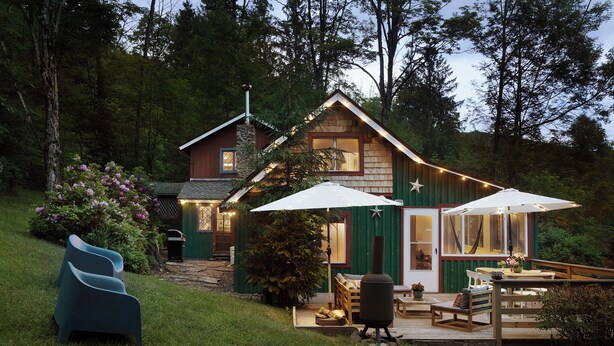 Eine rustikale Holzhütte mit einer Terrasse, Sitzgelegenheiten im Freien und einem Grill.