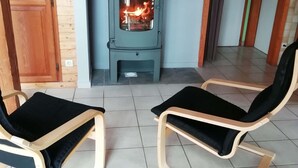 Una habitación con estufa de leña, dos mecedoras y una puerta de madera.