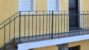 Un bâtiment jaune avec un balcon, une porte et une fenêtre.