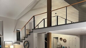 A spacious living area with a high ceiling, a staircase leading to an upper level, and a cozy seating arrangement. - The Highland Loop Experience on Ottertail Lake (Battle Lake)