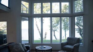 A room with a large bay window, a round coffee table, and two armchairs. - The Highland Loop Experience on Ottertail Lake (Battle Lake)