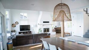 A spacious living area with a large wooden dining table, a comfortable sofa, a flat-screen TV, and a wicker pendant light. - The Highland Loop Experience on Ottertail Lake (Battle Lake)