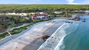 An aerial view of a coastal resort with a large building, multiple cabins, and a sandy beach. - White Point Beach Resort (Hunts Point)