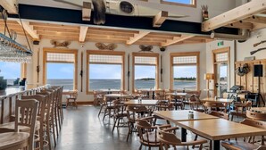 A spacious dining area with large windows, wooden furniture, and a view of the sea. - White Point Beach Resort (Hunts Point)
