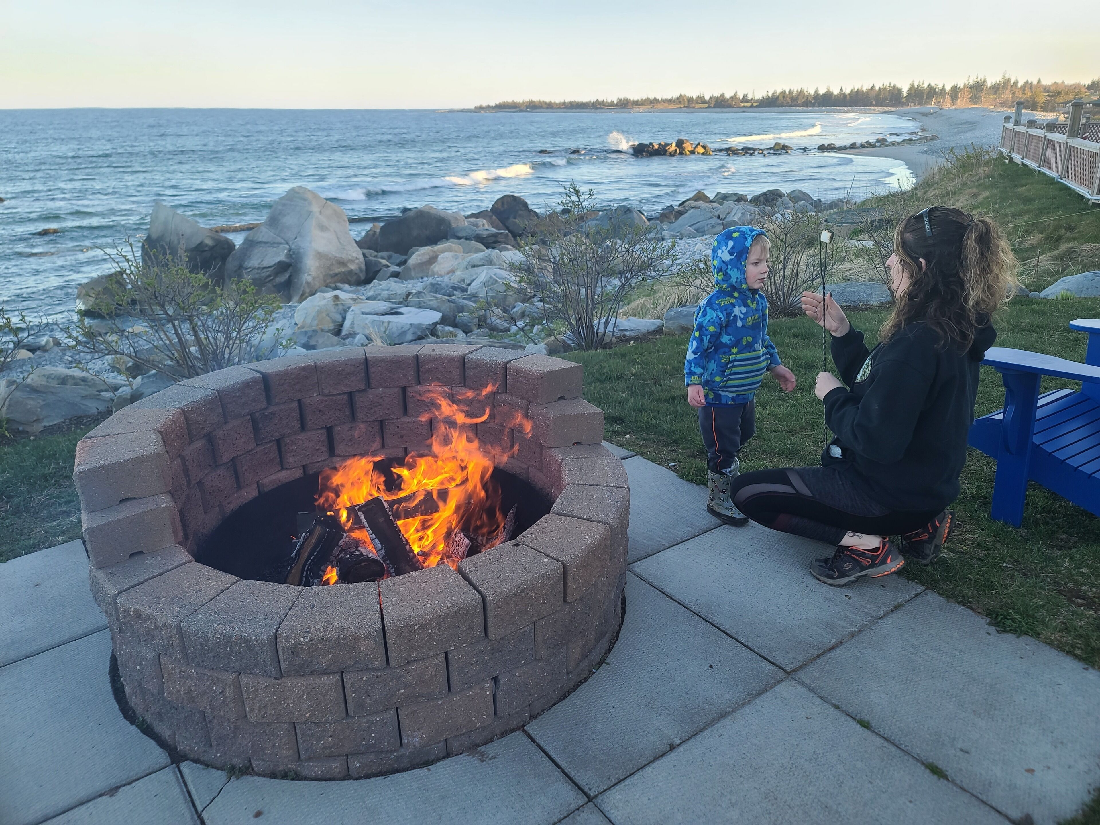 A fire pit with a view of the ocean and rocky shoreline.