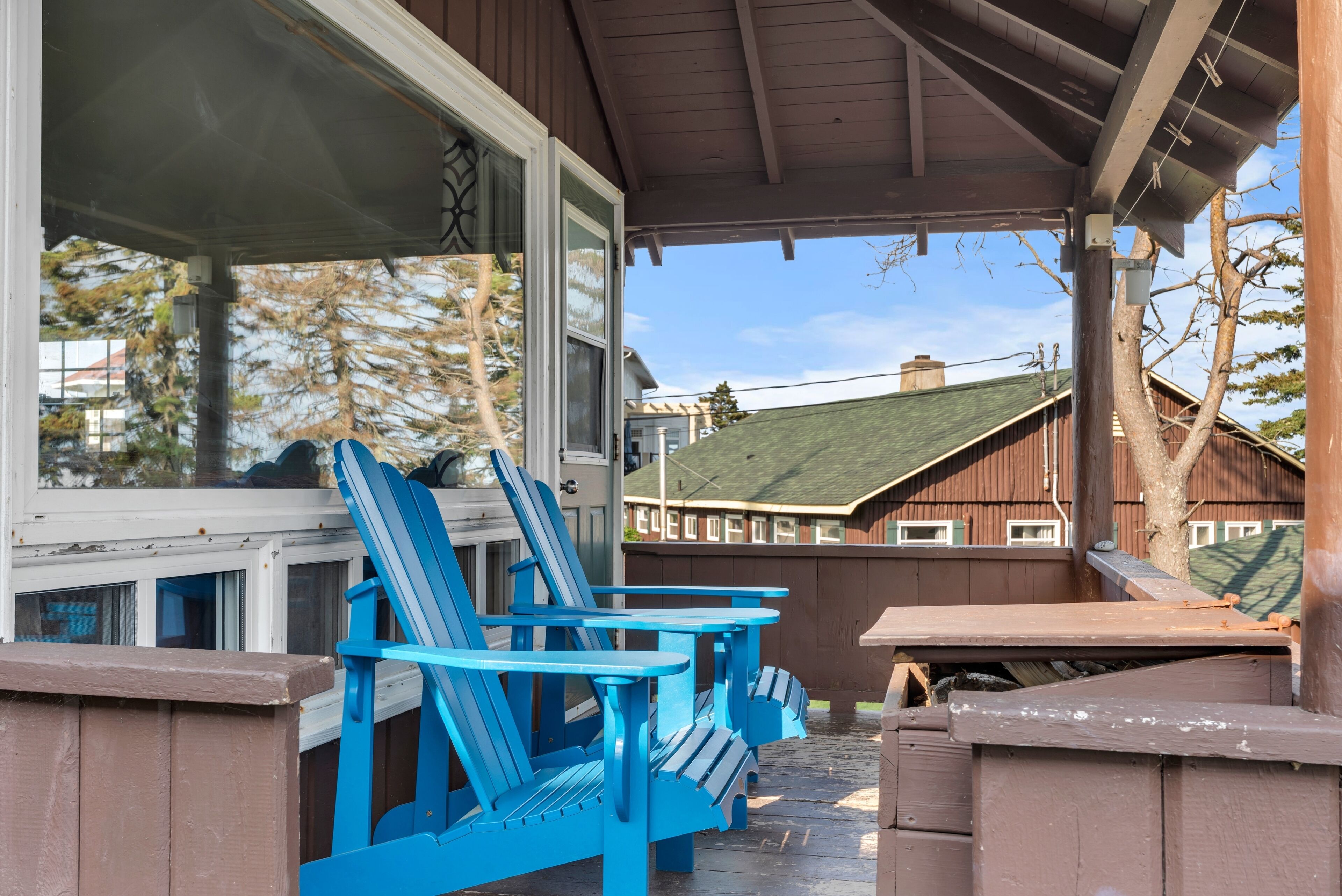 Un espace extérieur abrité, aménagé avec des chaises Adirondack bleues et une table de pique-nique.