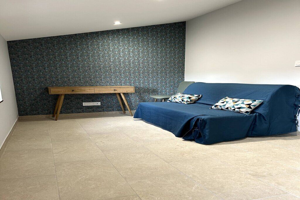 Una stanza con un divano blu, una panca di legno e un muro decorato.