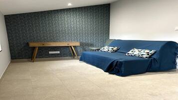 Una stanza con un divano blu, una panca di legno e un muro decorato.