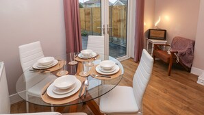 A dining area with a glass table set for four, surrounded by white chairs. - Sŵn Y Môr (Burry Port)