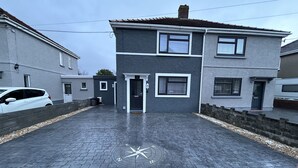 A two-story residential building with a paved driveway and a compass marking on the ground. - Sŵn Y Môr (Burry Port)