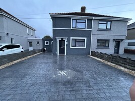 A two-story residential building with a paved driveway and a compass marking on the ground.