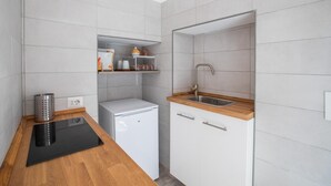 A compact kitchen with white cabinets, a built-in sink, and a small refrigerator.