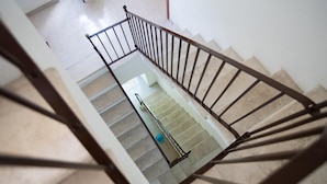 A staircase with a metal railing, beige steps, and a blue object on the landing.