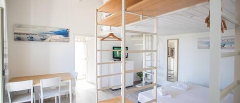 Una habitación con una litera, un escritorio con sillas, un televisor y un cuadro en la pared.