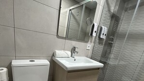 A modern bathroom with a toilet, sink, and glass shower enclosure. - Habitación con Jacuzzi y Baño Privado (Madrid)
