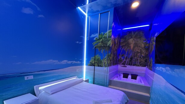 A bedroom with a bed, a small bedside table, and a bathtub. - Habitación con Jacuzzi y Baño Privado (Madrid)