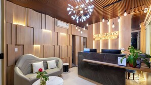 A reception area with a modern design, featuring a reception desk, a sofa, and a coffee table. - Full Moon Apartments (Da Nang)