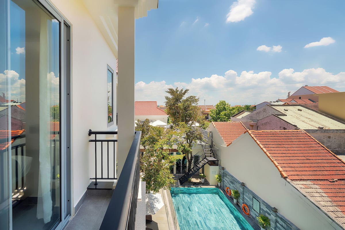 A balcony with a view of a swimming pool, a staircase, and neighboring buildings.