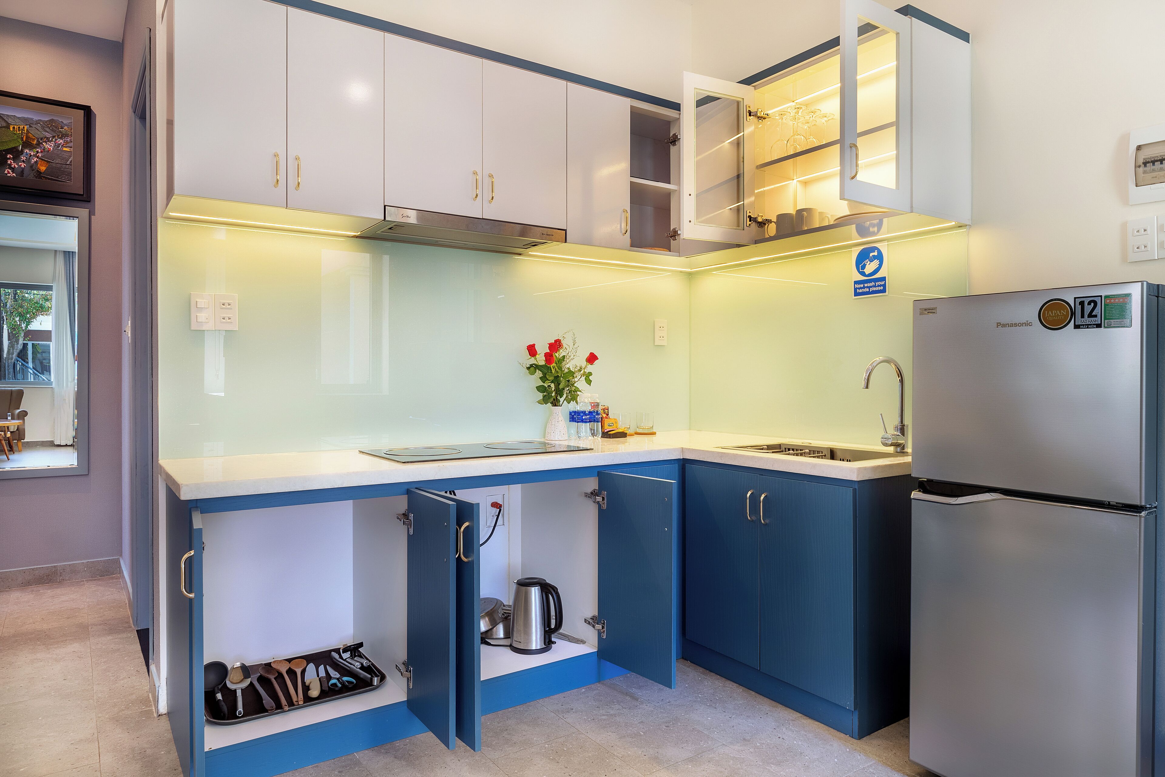 A compact kitchen with a refrigerator, a sink, and a stove. There are cabinets and a countertop.