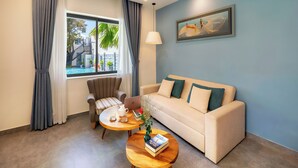 A living room with a sofa, two coffee tables, a chair, a laptop, and a window with curtains. - Full Moon Apartments (Da Nang)