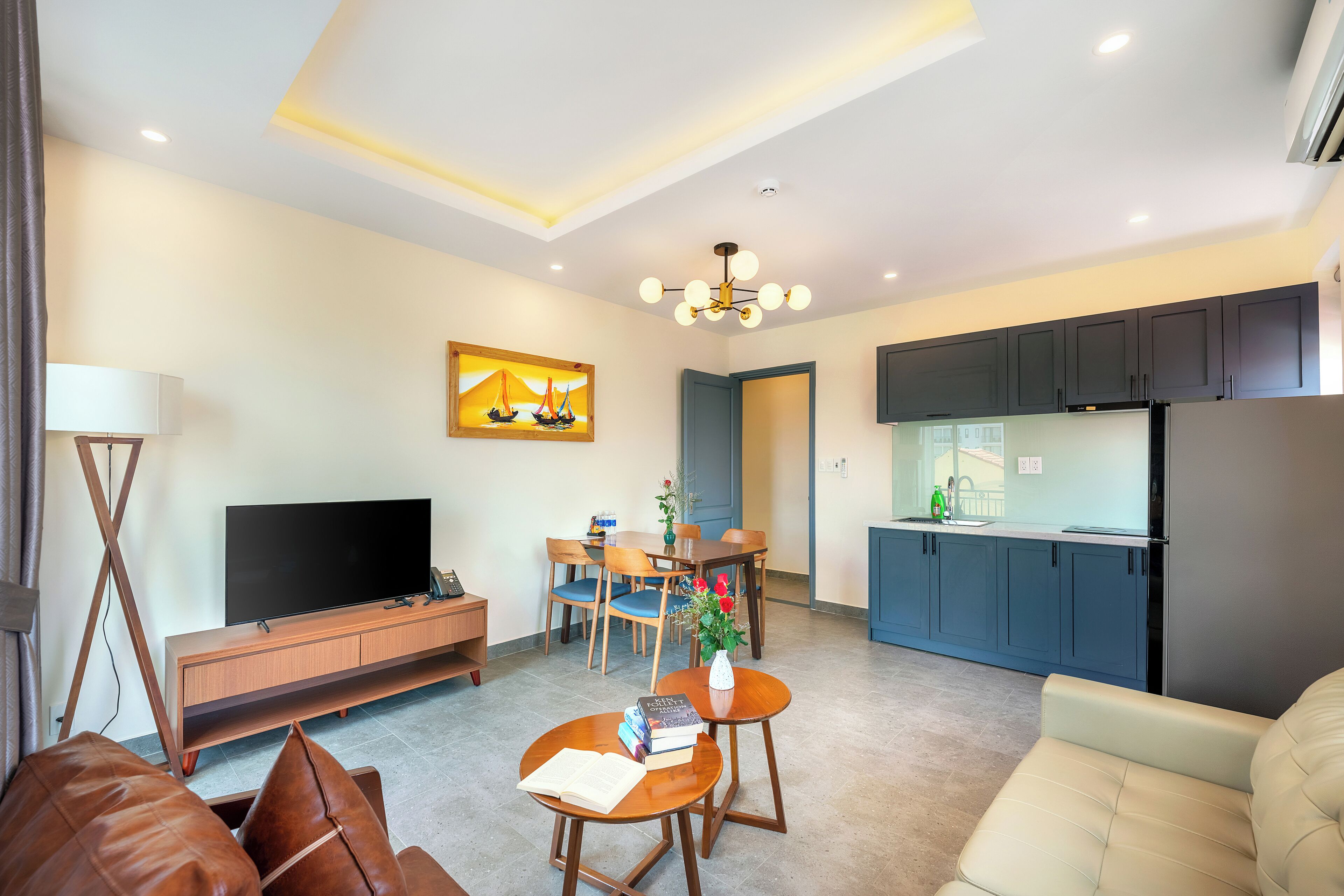 Una sala de estar moderna con televisor de pantalla plana, muebles de madera, un comedor y una cocina con armarios oscuros.