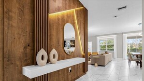 Un interno moderno con una parete in legno a contrasto, uno scaffale bianco con oggetti decorativi e un grande specchio.
