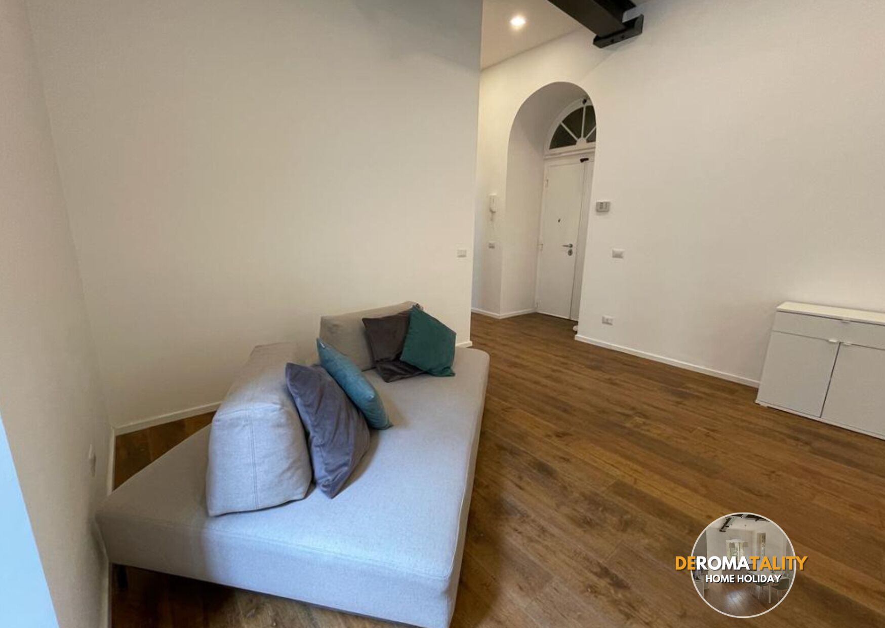 Una sala de estar moderna con un sofá, almohadas y suelo de madera.