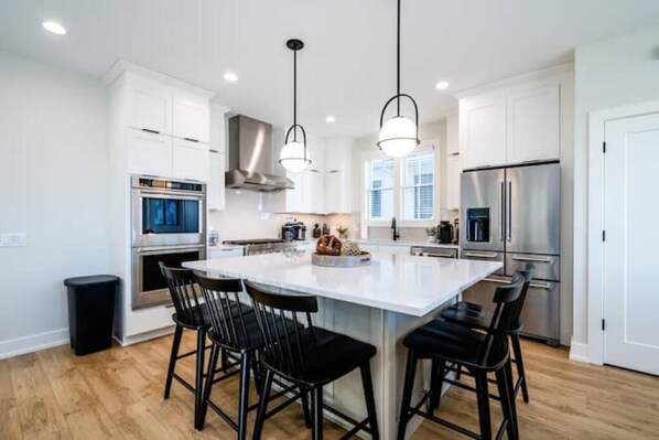 A modern kitchen with white cabinets, stainless steel appliances, and black bar stools. - High End Home on Water & Pool! 7 night minimum. Sunday to Sunday (Saint Joseph)