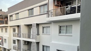 A multi-story residential building with balconies, air conditioning units, and a visible staircase.