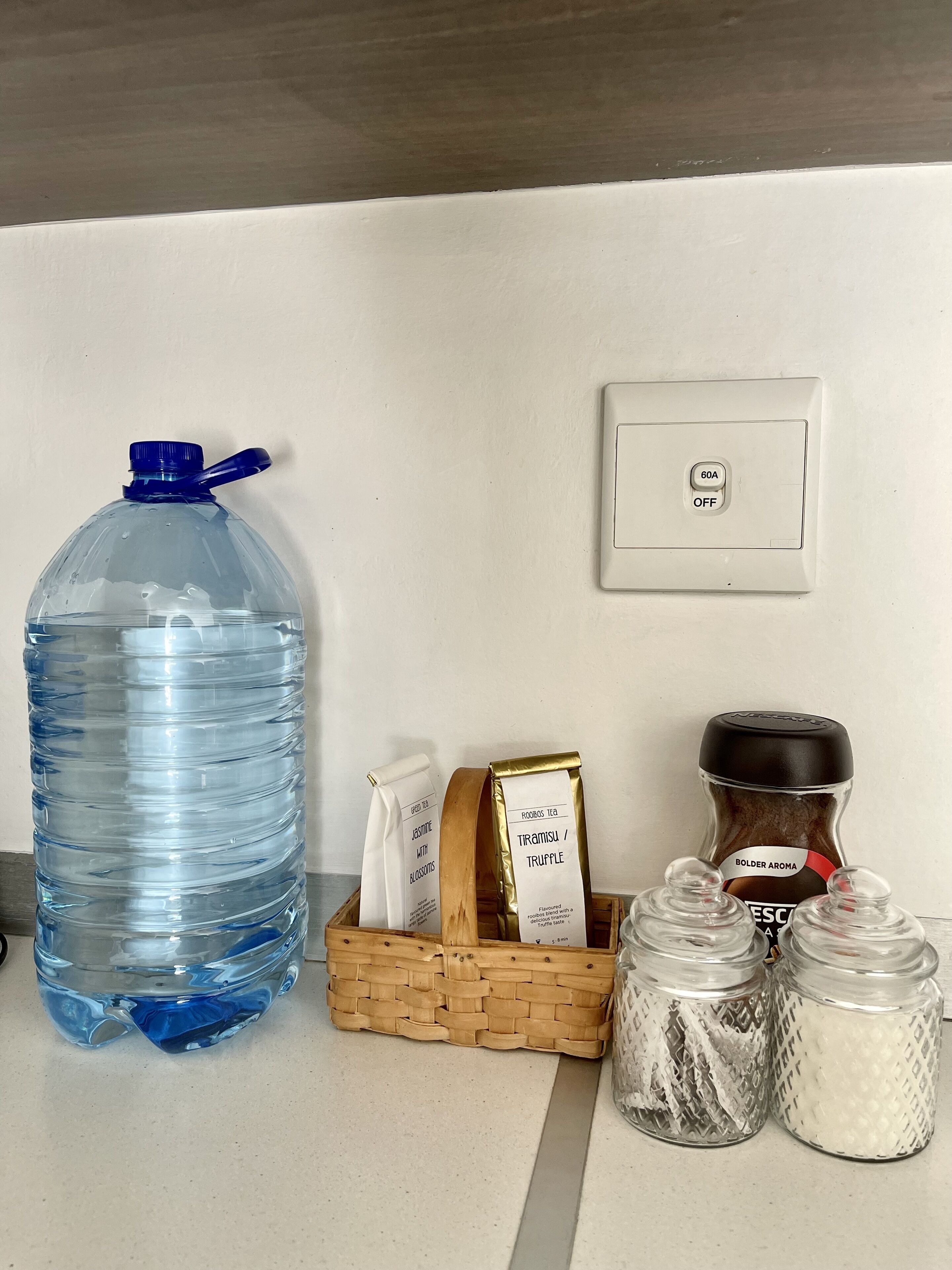 A kitchen counter with a large water bottle, a coffee maker, a tea bag, and salt and pepper shakers.