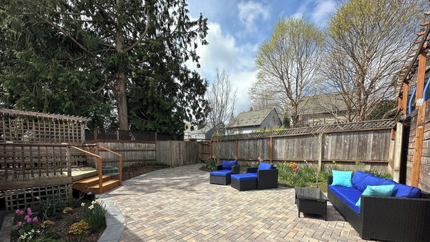 Une terrasse avec un sol en briques, des meubles d’extérieur et une clôture en bois.